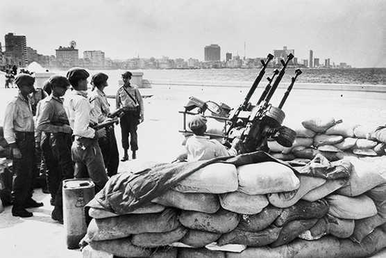 On Havana waterfront, Cuban soldiers wait by anti-aircraft artillery, after receiving warning of an invasion from the United States