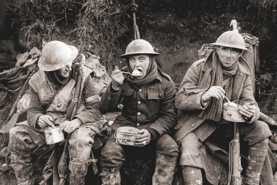 Soldiers in First World War uniform eat in the trenches